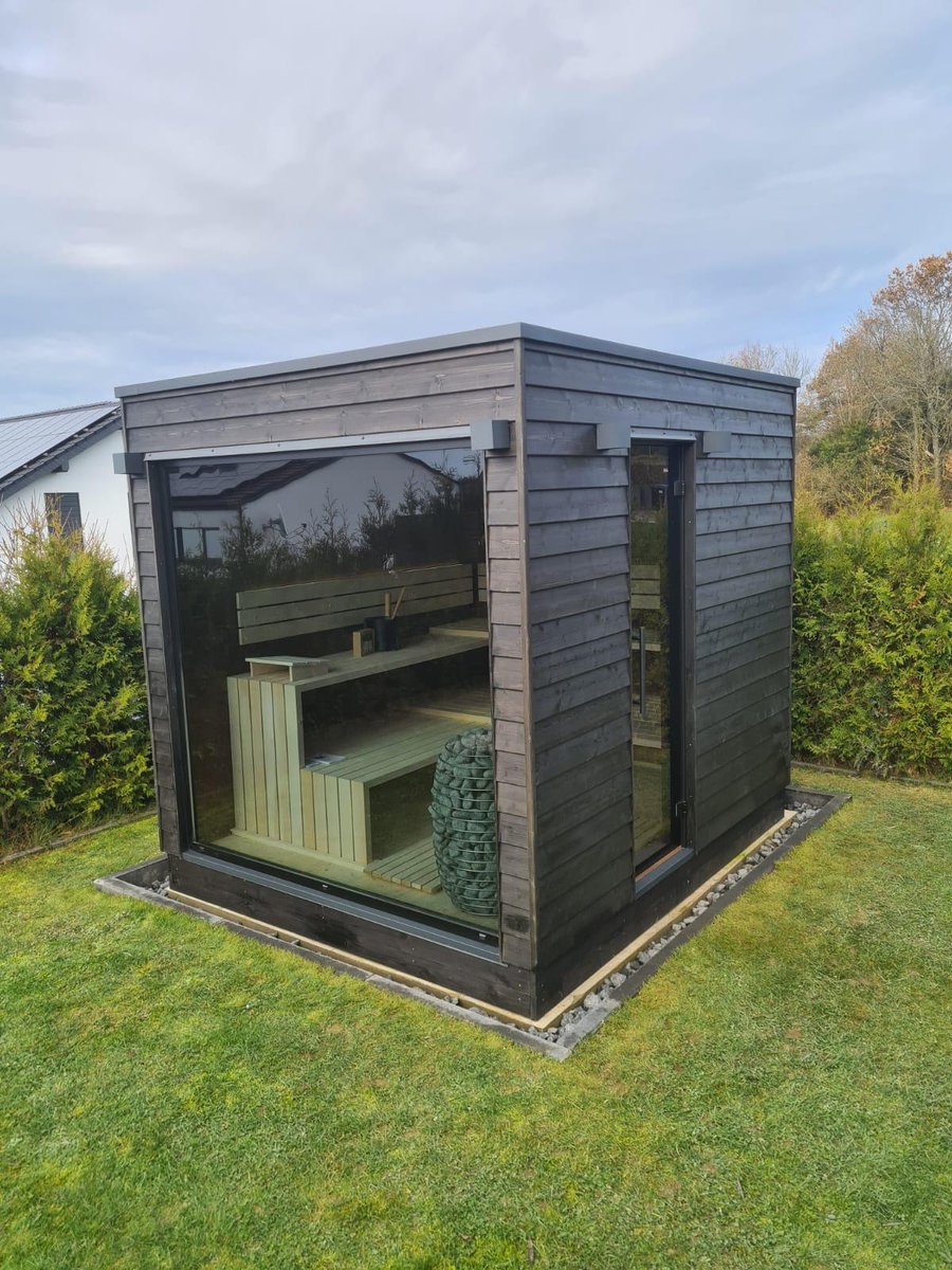 Sauna NELA s tmavým dřevěným obkladem, velkým oknem a bočními dveřmi